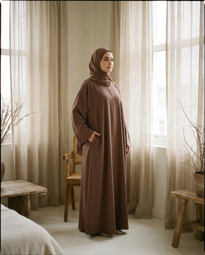 Woman wearing cocoa umbrella-cut summer abaya with hand in hidden pocket