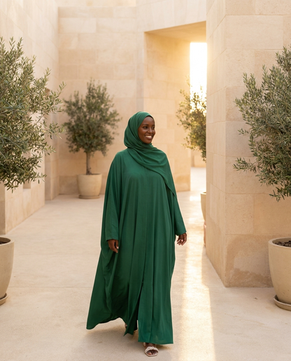 Woman wearing emerald umbrella-cut summer abaya in warm golden light