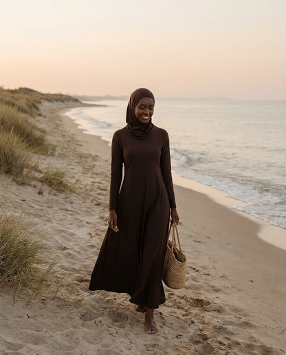 Woman wearing espresso full-coverage burkini with swim hijab walking on the beach