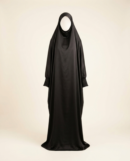 Black one-piece hooded prayer jilbab with smocked sleeves on invisible mannequin